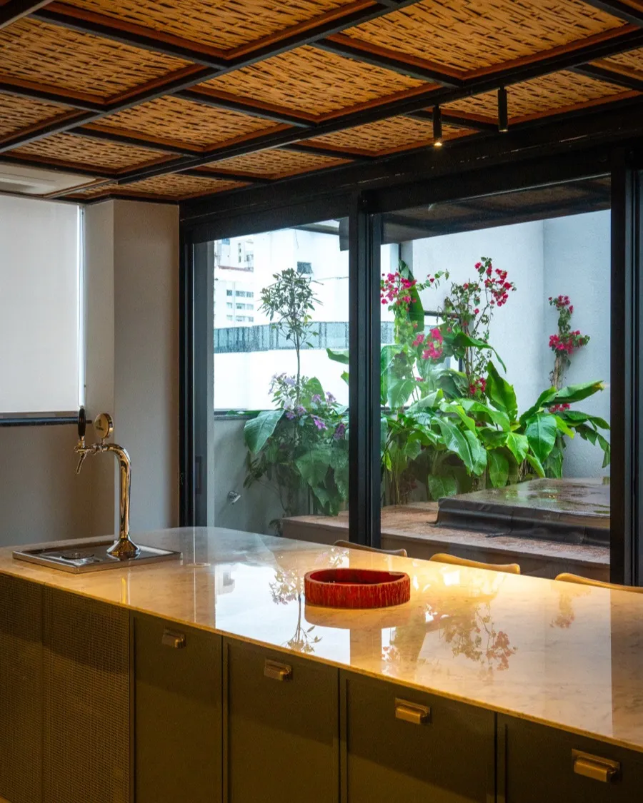 Cozinha em tom oliva com o jardim de inverno emoldurado pela janela