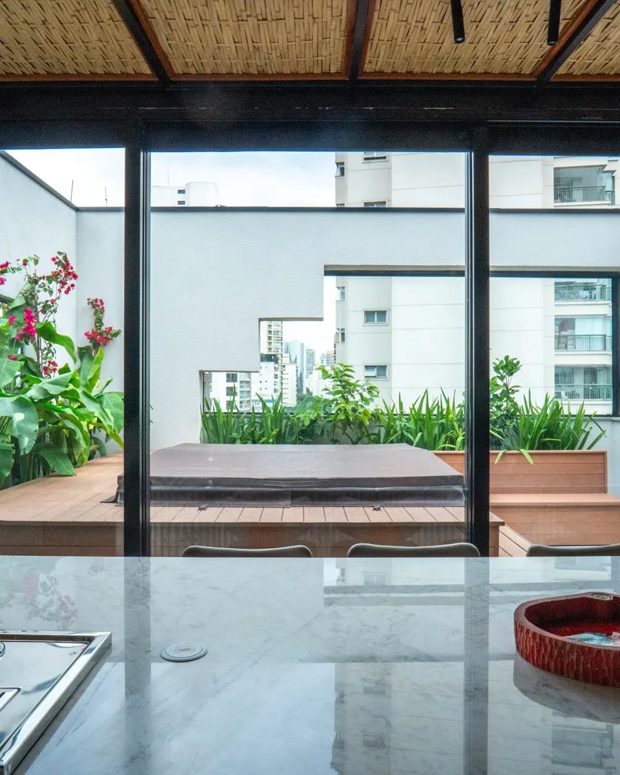 Ilha em mármore e o terraço com deck ao fundo