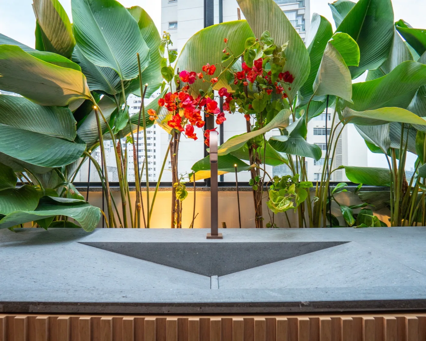 Jardim de inverno iluminado ao entardecer, com recorte triangular em pedra na bancada