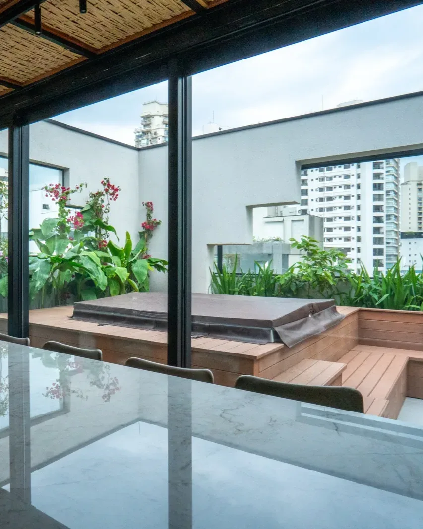Projeto Bougainvillea — bancada da churrasqueira com vista para o deck e o jardim florido