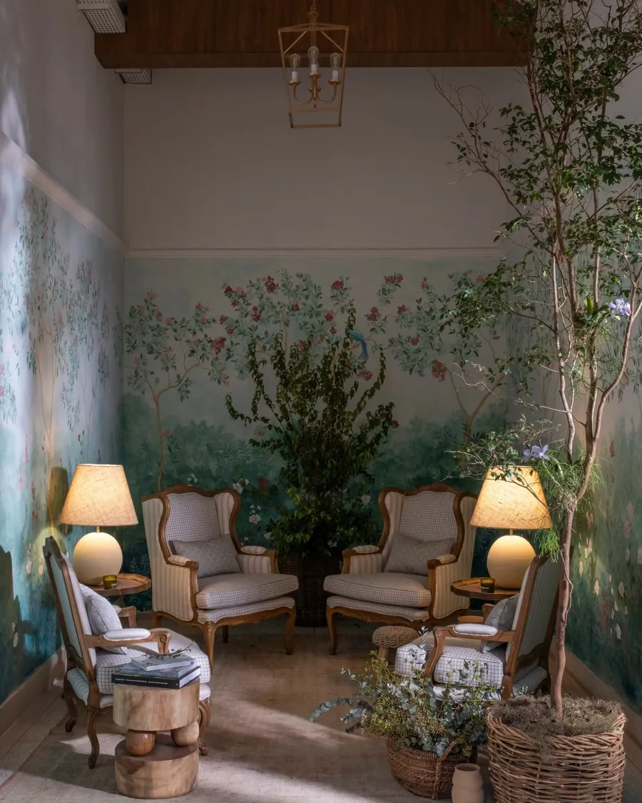 Poltronas dispostas em torno de uma árvore nativa, sob o pé-direito alto e a chinoiserie