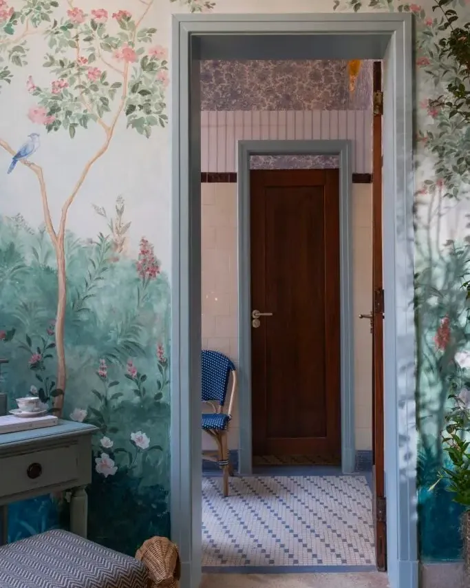 Passagem emoldurada pela chinoiserie para o banheiro restaurado, com porta de madeira maciça e piso em mosaico original